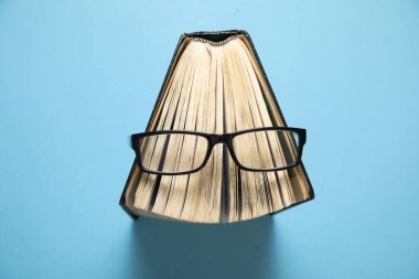 Mavi arka planda gözlük ve kitap.
