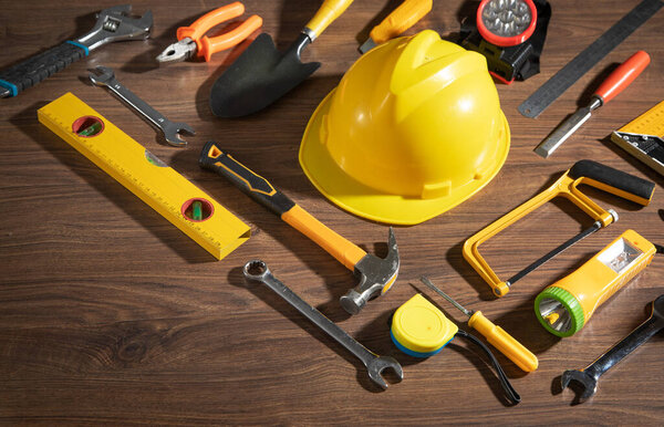 Work tools with helmet on wooden background.