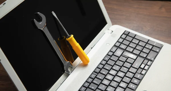 Wrench and screwdriver with a laptop computer. IT Service. Support