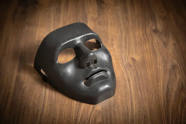 Schwarze Maske Auf Dem Holztisch — Stockfoto