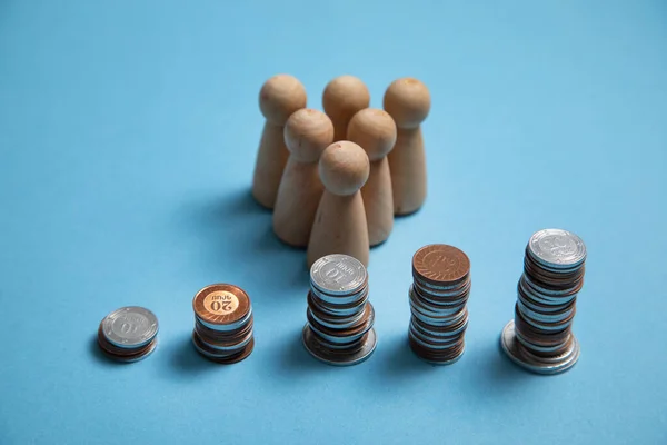 Wooden human figures with a stack of coins.