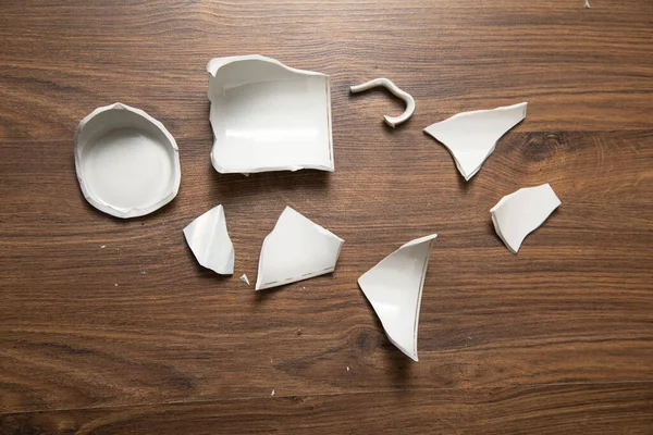 Ahşap arka planda beyaz kırık bardak..