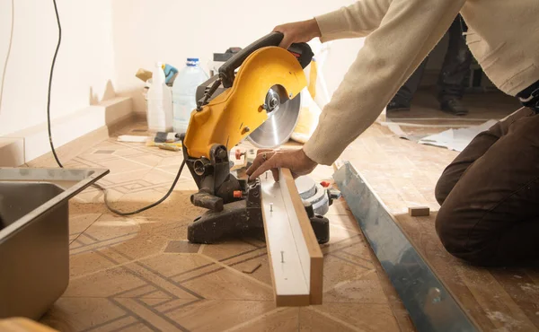 Mobilyanın bir kısmını kesme makinesiyle kesen işçiler.