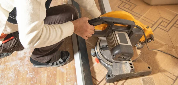 Mobilyanın bir kısmını kesme makinesiyle kesen işçiler.