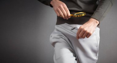 Man with a magnifying glass looking his penis.