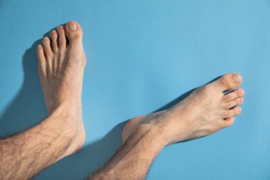 Mavi arka planda yalınayak bir erkek.