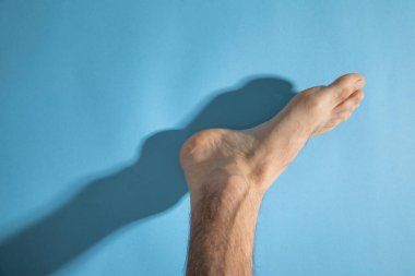 Mavi arka planda yalınayak bir erkek.