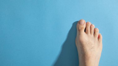 Mavi arka planda yalınayak bir erkek.