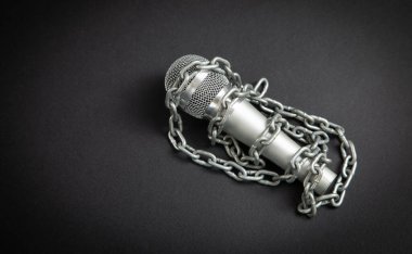 Siyah arka planda zincirlerle bağlı mikrofon.