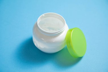 Mavi arkaplanda krema kavanozu.