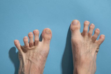 Mavi arka planda yalınayak bir erkek.