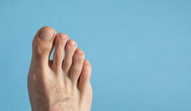 Mavi arka planda yalınayak bir erkek.