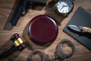 Tabanca, bıçak, kelepçe, yargıç tokmağı, ahşap masadaki çalar saat..