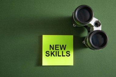 Yapışkan notta dürbünle yeni beceriler mesajı.