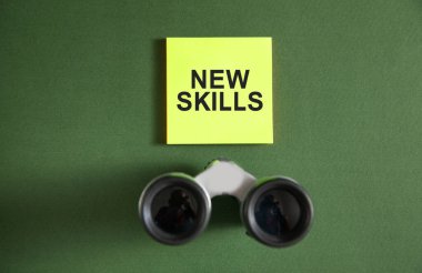 Yapışkan notta dürbünle yeni beceriler mesajı.