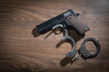 Ahşap arka planda kelepçe ve tabanca..