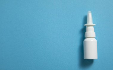 Mavi arka planda beyaz burun spreyi şişesi..