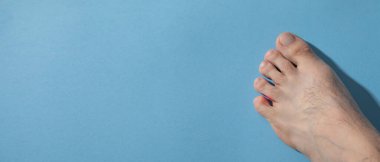 Mavi arka planda yalınayak bir erkek.