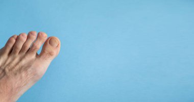 Mavi arka planda yalınayak bir erkek.