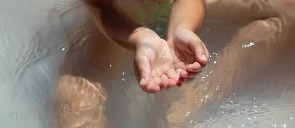 Baby hands in the water in the inflatable pool.