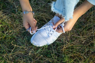 Dışarıda ayakkabı bağlayan kadın..