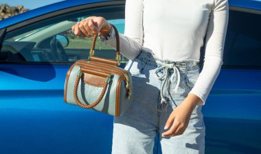 Arabanın yanında çantalı bir kadın var..