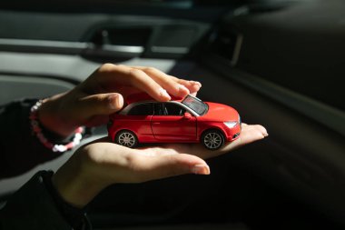 Beyaz kadın eli kırmızı oyuncak araba gösteriyor..