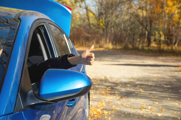 Женщина внутри машины с большим пальцем вверх жестом.