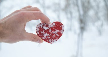 Erkek eli kışın kırmızı kalbi gösterir..