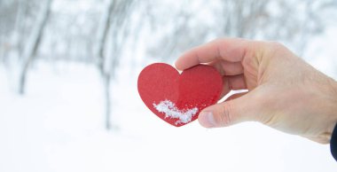 Erkek eli kışın kırmızı kalbi gösterir..
