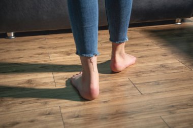 Çıplak ayaklı kadın evde yerde yürüyor..