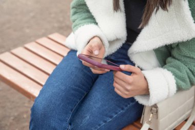 Açık havada cep telefonu kullanan beyaz bir kadın..