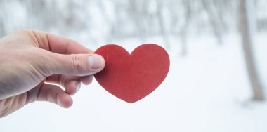 Erkek eli kışın kırmızı kalbi gösterir..