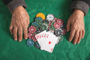 Kumarhane fişleri ve kartları tutan yaşlı kadın elleri.