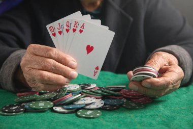 Kumarhane fişleri ve kartları tutan yaşlı kadın elleri.