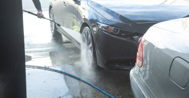 Beyaz adam araba yıkama istasyonunda araba yıkıyor..