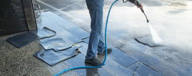 İstasyonda lastik araba paspası yıkayan bir işçi..  