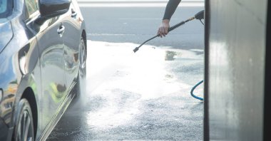 Beyaz adam araba yıkama istasyonunda araba yıkıyor..