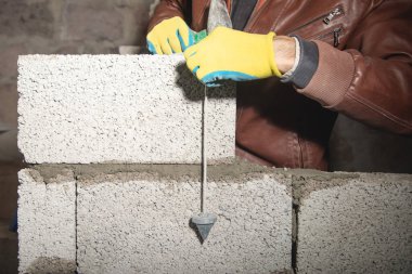 İşçi inşaat sahasına duvar örüyor..