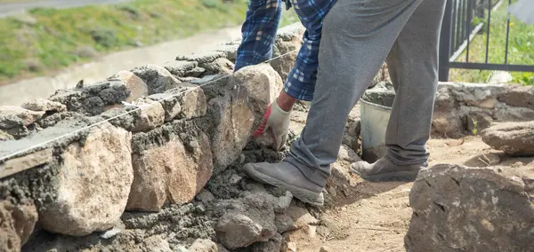 İşçi inşaat sahasına duvar örüyor..