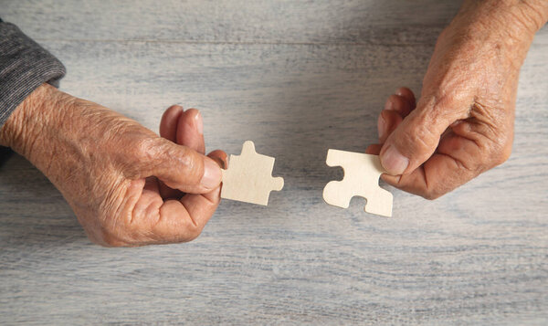 Руки старушки с пазлом.