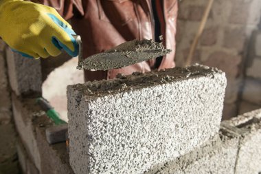 İşçi inşaat sahasına duvar örüyor..