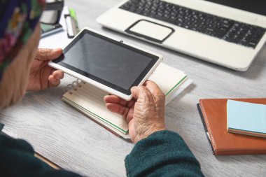 Dijital tablet kullanan Kafkasyalı yaşlı kadın.