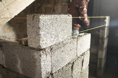 İşçi inşaat sahasına duvar örüyor..