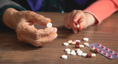 Elinde ilaç tutan yaşlı kadın ve genç kızın elleri..