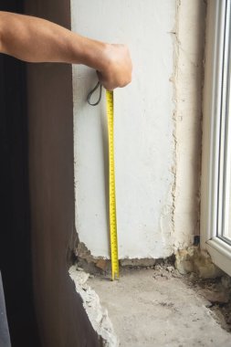 Evdeki yenilemeden önce eski pencere pervazını ölçen işçiler.