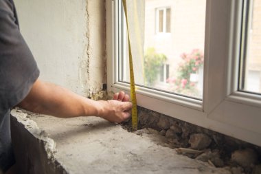 Evdeki yenilemeden önce eski pencere pervazını ölçen işçiler.