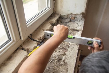 Evdeki yenilemeden önce eski pencere pervazını ölçen işçiler.