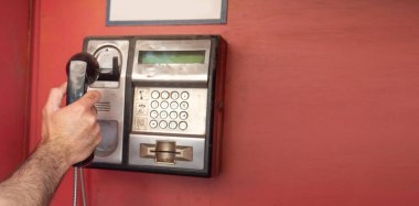 Şehir caddesinde eski bir ankesörlü telefonu kullanan adam..