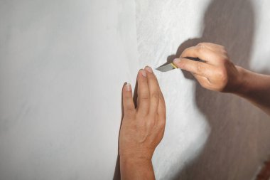 Beyaz işçi evdeki duvarlara duvar kağıdı yapıştırıyor..